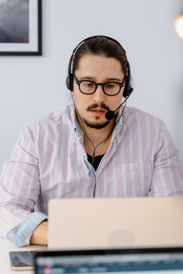 Professional customer support agent working remotely with headset and laptop, focusing on providing excellent service.